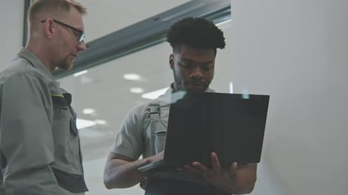 Two Men Discussing Technology in Modern Office Setting