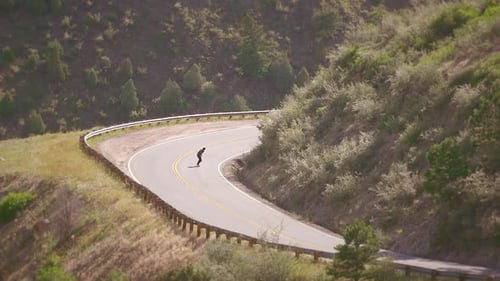 One skateboarder guy bombing a steep hill in Colorado backcountry on a skateboard