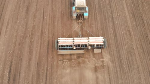 Aerial View of Tractor with Mounted Seeder Performing Direct Seeding of Crops on Plowed Agricultural