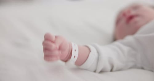 Baby, new born and hand with bracelet on bed for care, trust or support in hospital for birth