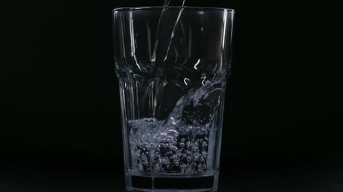 Water Being Poured into Glass on Black Background