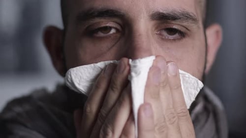 Nahaufnahme eines Mannes, der niest, hustet und sich die Nase putzt. Krankheitskonzept