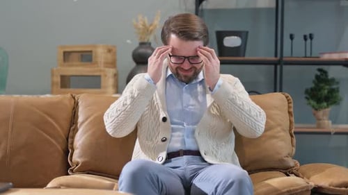Man suffering from a headache sitting on couch