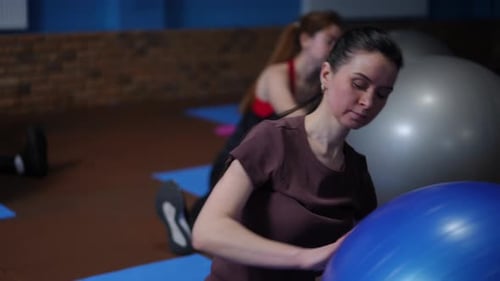 Fitnesstraining mit einem Gymnastikball aus sitzender Position Eine Gruppe von Frauen in Sportbekleidung sitzt