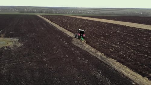 Red tractor plowing the field in Ukraine