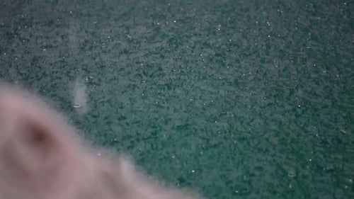 Starker Regen in Zeitlupe trifft auf die Oberfläche des Schwimmbeckens