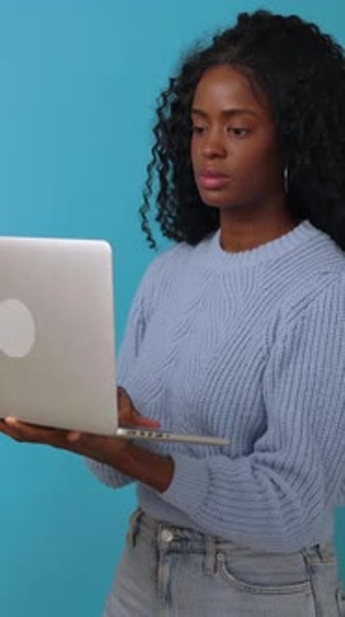Happy Young Latin African Woman Using Laptop Over Blue Background