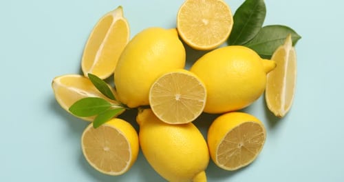 Bright Yellow Lemons Sliced on Light Blue Background