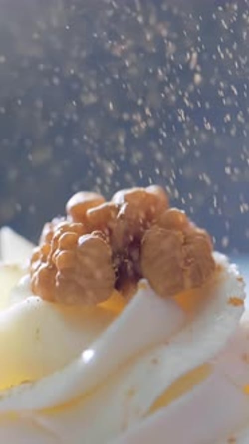 Cupcake with frosting and walnuts gets sparkly sprinkles