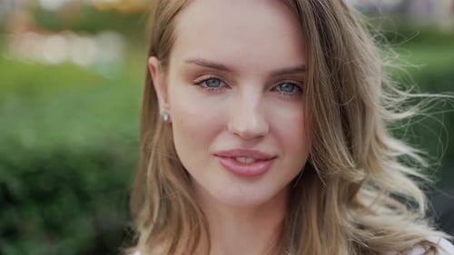 Gros plan du visage d'une femme, cheveux soufflés par le vent, visage souriant et cils flottants