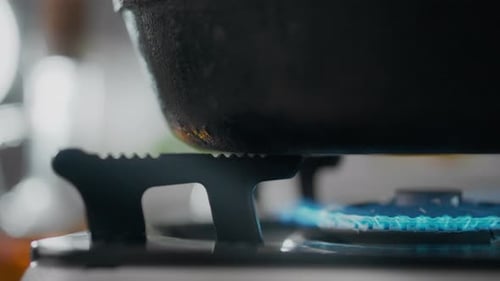 In the kitchen of the house, a gas stove is igniting the gas with a blue flame, the moment the gas
