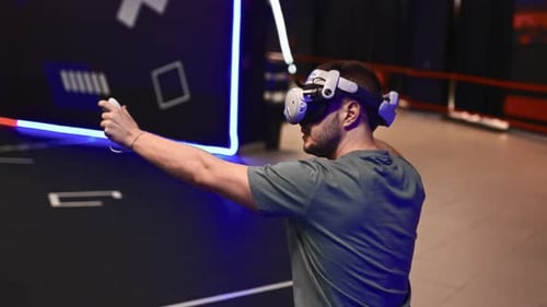 Man Fully Immersed in VR Shooter Game at Virtual Reality Lounge Wearing Headset and Motion