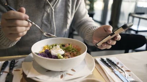 Young man browsing internet on smartphone during lunch break in modern cafe