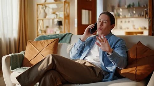 Man Talking on Phone Relaxing on Living Room Couch