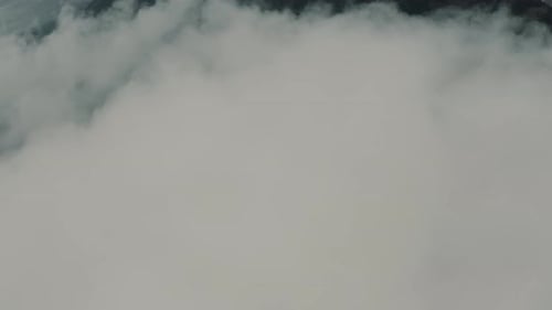 Drone aerial view flying high over clouds revealing beautiful landscape with mountains