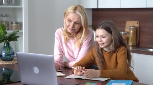 Woman Helps Girl with Homework in Bright Kitchen