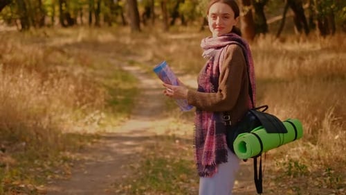 a woman in the forest with a map, a girl drinking tea in the forest, a topographic map in her hands,