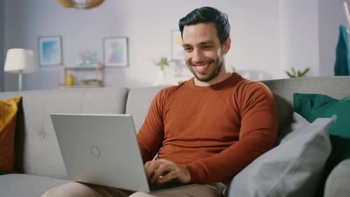 Man Smiling while Using Laptop on Couch