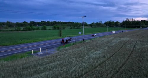 Amish horse and buggy on road. Cars pass Amish family on rural road in America. Dark storm clouds in