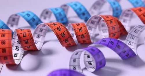 Colorful Measuring Tapes Curled on a White Surface