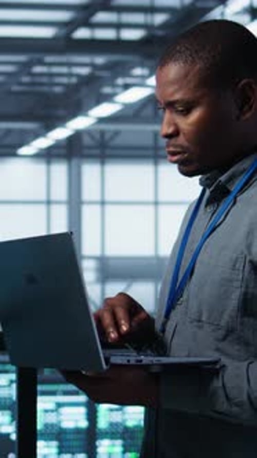 Vertical Video Team of Technicians Working in Server Farm Using Laptops to Analyze Data
