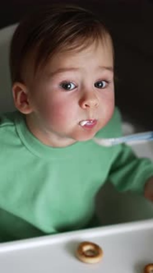 Infant being fed with a spoon in high chair