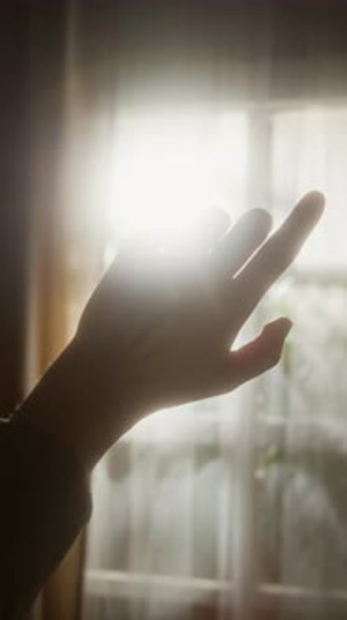 Hand Waving against Soft Sunlight through Window Vertical