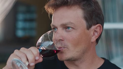 Man drinking red wine indoors in close up