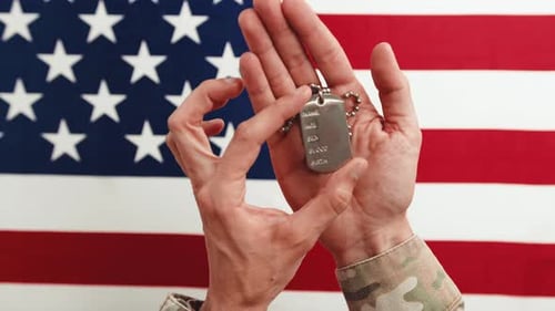 Hands Hold Dog Tags Before American Flag