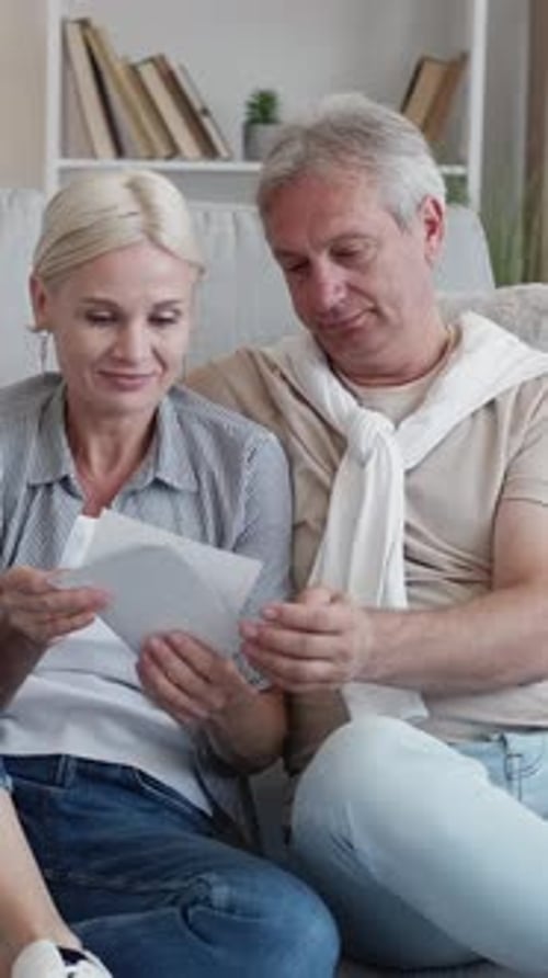 Mature Couple Looking Through Photographs Together at Home