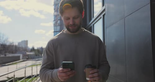 Man Using Phone with Coffee Outdoors