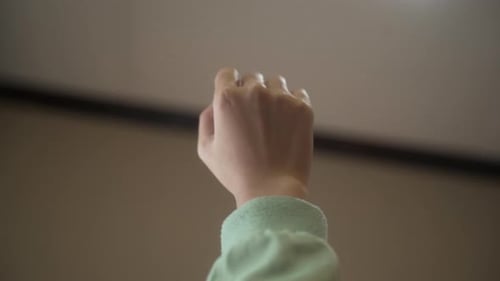 Close Up Of Female Hand In Fist Opening With Forearm Upward Against Blurry Background.
