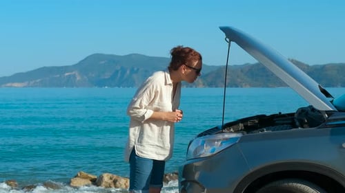 Woman Looks at Car Engine on a Beach