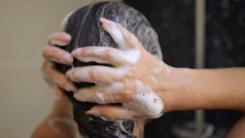 Woman Washing Hair with Shampoo in Shower