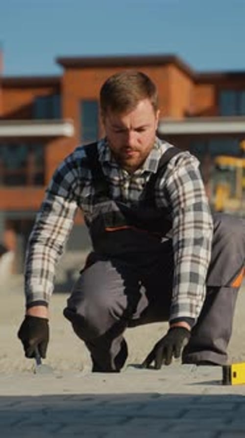 Worker Adjusting Paving Stones in a Country Cottage Town