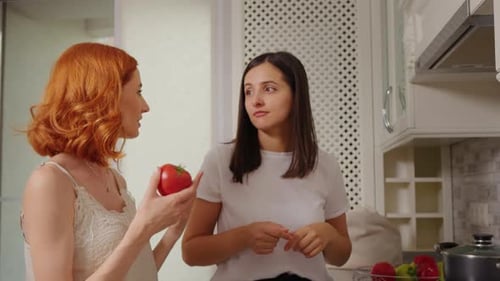 Mittlere Aufnahme in der Küche von zwei Frauen, die über Rezepte diskutieren.
