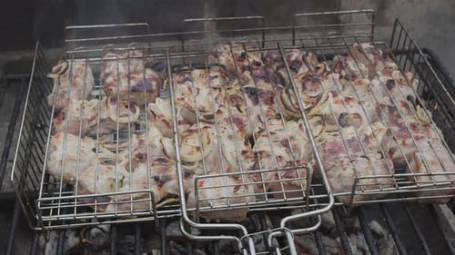 Meat kebab is on a grill grate and burning barbecue coals under it close up.