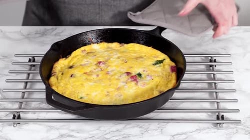 Frittata aux épinards et au jambon fraîchement cuite dans une poêle en fonte