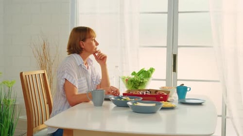 Pensive Woman Sitting at Table with Food