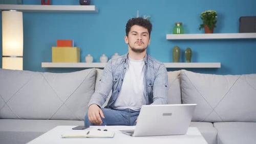 Young Adult Celebrating Success with Laptop at Home