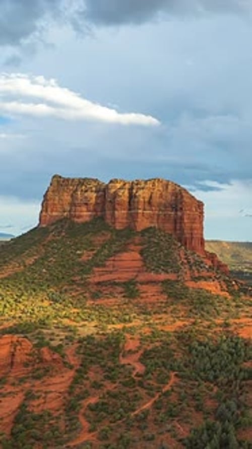 Courthouse Butte Rises Above Scrubby Desert Slopes, Standing Boldly Beneath a Soft, Cloud-dotted