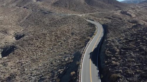 Black car driving on desert road in California. Road trip concept. Aerial drone view