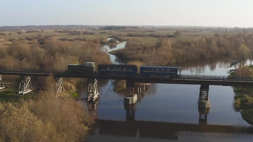 Aerial View of a Train Traveling Over a Railway Bridge Over a River