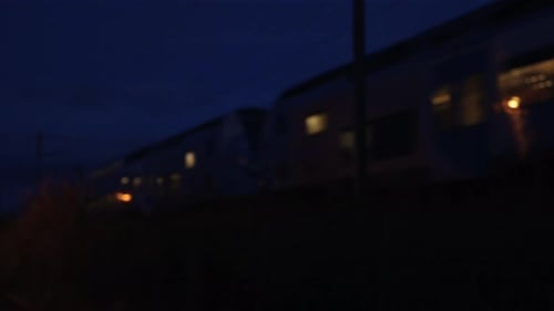 Abendzug, der durch eine eingezäunte Eisenbahnlinie in einer ruhigen Stadtgegend fährt