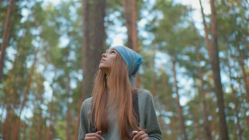 Young Woman Hiking Through Lush Forest Looking Upward in Peaceful Environment