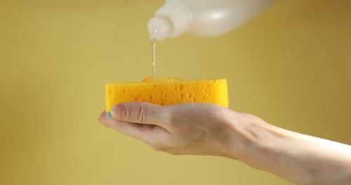 Pouring Dish Soap on a Yellow Cleaning Sponge