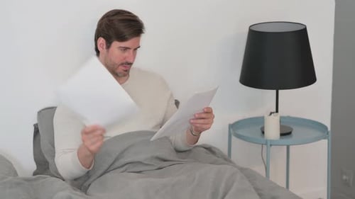 Adult Reads Document in Bed