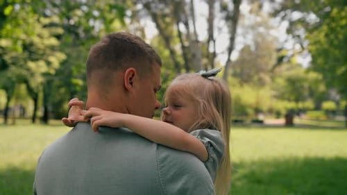 Loving Father Hugs Daughter in Sunny Park