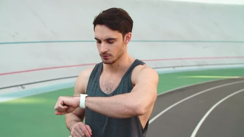 Man Runner Checks Smartwatch at Stadium