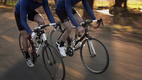 Steadicam of Two Healthy Men Peddling Fast /Free Wheeling with Cycling